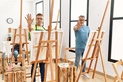 Group of middle age people artist at art studio with open hand doing stop sign with serious and confident expression, defense gesture