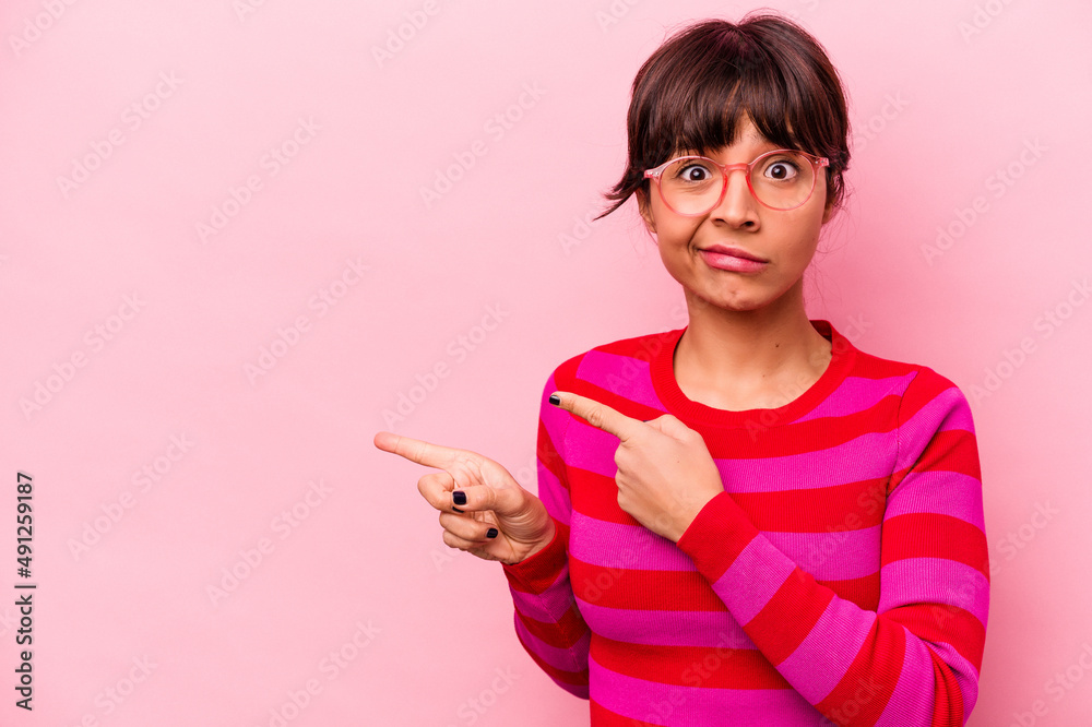 Young hispanic woman isolated on pink background shocked pointing with index fingers to a copy space. Young hispanic woman isolated on pink background shocked pointing with index fingers to a copy space.