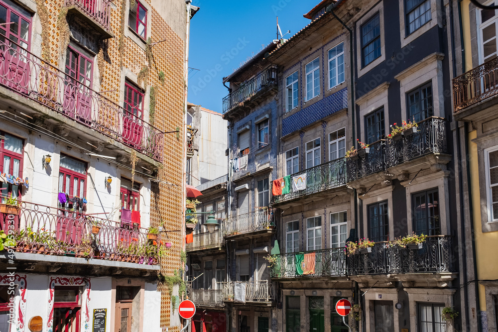 Colorful facades of residential apartments with traditional Portuguese tile in the old town. Flower pots in the balconies, national flags and clothes hanging.