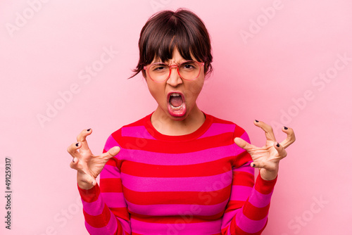 Young hispanic woman isolated on pink background screaming with rage.