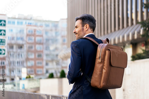 Obraz na plátně Businessman with backpack walking in city