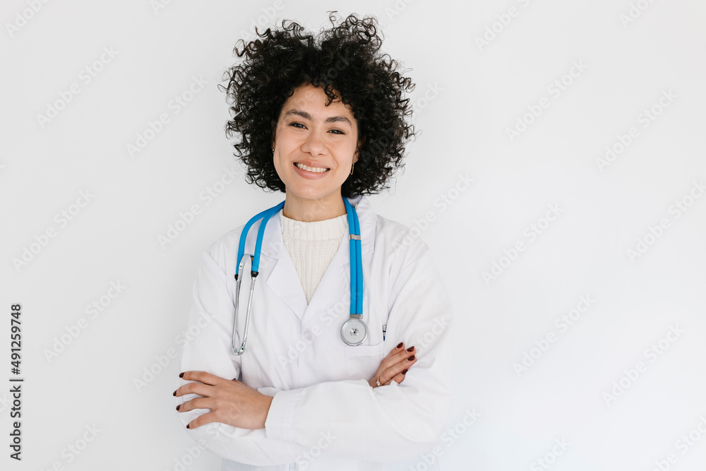 Smiling doctor standing with arms crossed in front of white wall Smiling doctor standing with arms crossed in front of white wall