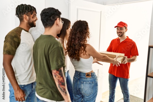 Group of people holding take away pizzas from deliveryman at home.