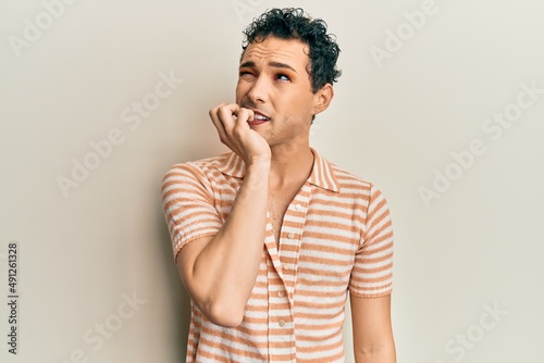 Handsome man wearing make up wearing casual t shirt looking stressed and nervous with hands on mouth biting nails. anxiety problem.