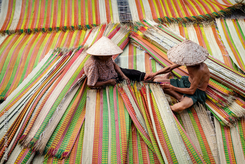 Vietnamese Old Man and Women Making a drying traditional vietnam mats in the old traditional village at dinh yen, dong thap, vietnam, tradition artist concept,Vietnam. photo