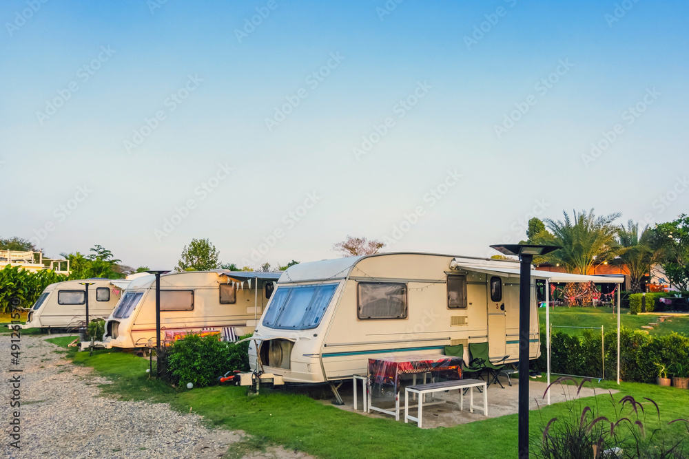 Cozy retro travel trailer Caravan on green grass before sunset near riverside in peaceful countryside. Family vacation travel RV, holiday trip in motorhome. Outdoor and Recreational Vehicles Theme. Cozy retro travel trailer Caravan on green grass before sunset near riverside in peaceful countryside. Family vacation travel RV, holiday trip in motorhome. Outdoor and Recreational Vehicles Theme.