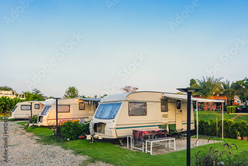 Cozy retro travel trailer Caravan on green grass before sunset near riverside in peaceful countryside. Family vacation travel RV, holiday trip in motorhome. Outdoor and Recreational Vehicles Theme.