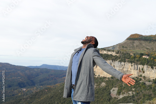 Euphoric man with black skin outstretching arms in winter