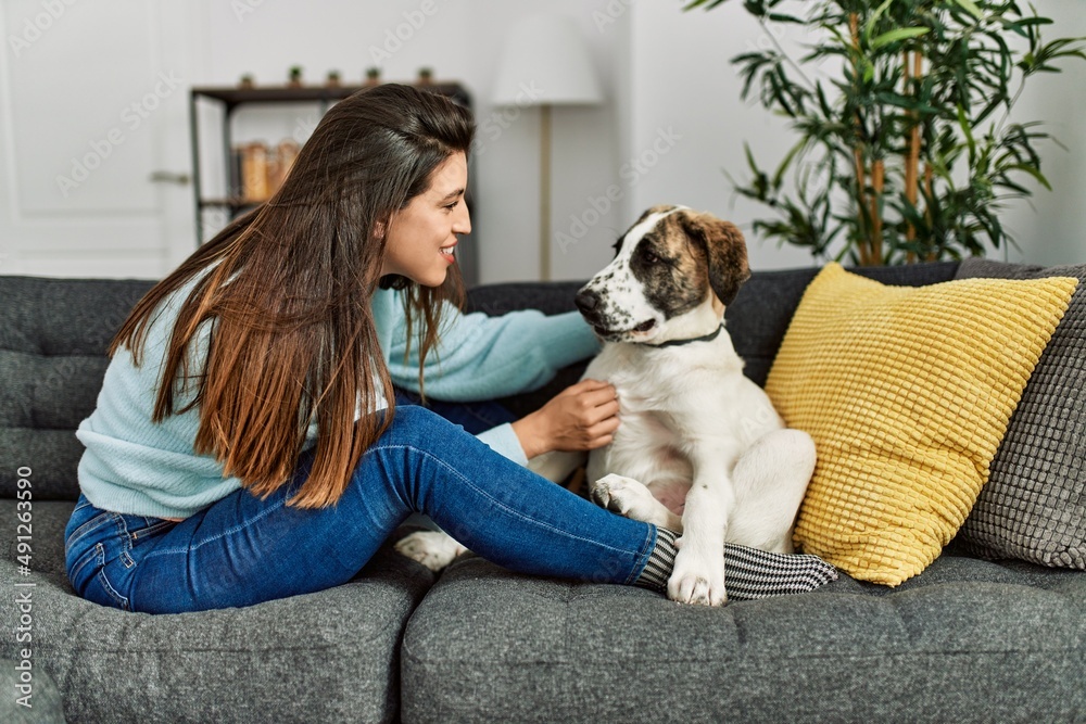 Young woman hugging dog sitting on sofa at home Young woman hugging dog sitting on sofa at home