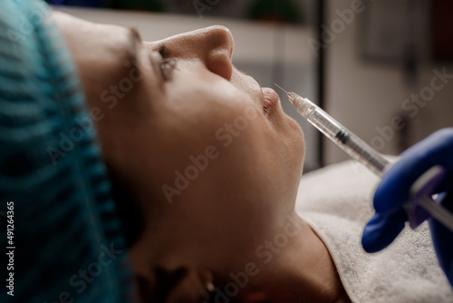 A cosmetologist injects a syringe into a patient