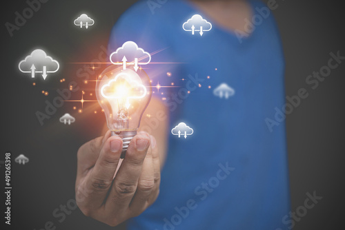 Technology business transformation concept. Innovation to the future. A man holding light bulb with virtual cloud computing to transfer database information upload, download application.