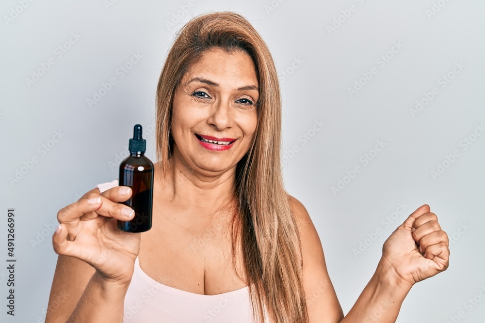 Middle age hispanic woman using night serum screaming proud, celebrating victory and success very excited with raised arm Middle age hispanic woman using night serum screaming proud, celebrating victory and success very excited with raised arm