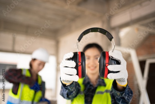 Pretty Asian Engineer,foreman Campaign to wear soundproofing equipment.Recommendations for wearing ear muffs.
Work safely with noise reduction.
a young woman using an electric screwdriver safely. photo