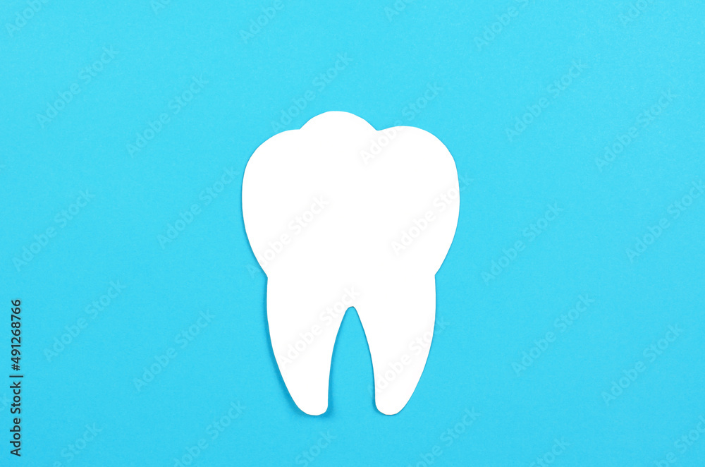 White tooth on a blue background. Dental care concept, copy space. White tooth on a blue background. Dental care concept, copy space.