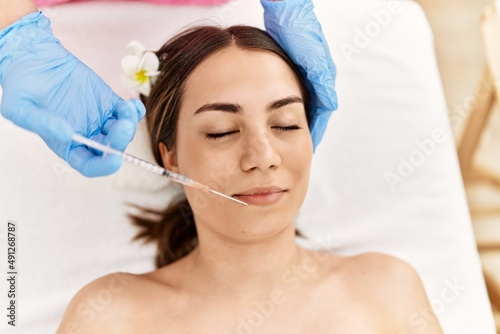 Young hispanic woman having anti-aging treatment at beauty center.