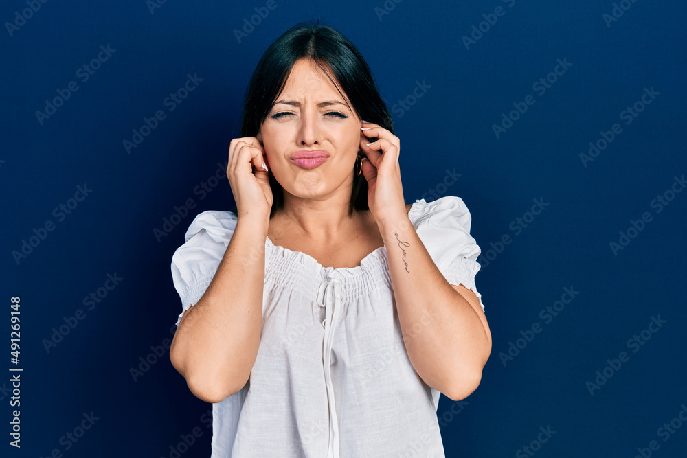 Young hispanic woman wearing casual clothes covering ears with fingers with annoyed expression for the noise of loud music. deaf concept. Young hispanic woman wearing casual clothes covering ears with fingers with annoyed expression for the noise of loud music. deaf concept.