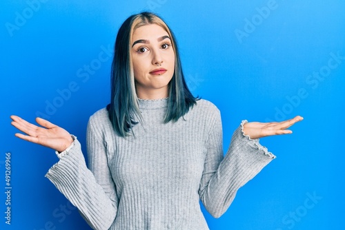 Young modern girl wearing casual sweater clueless and confused with open arms, no idea and doubtful face.
