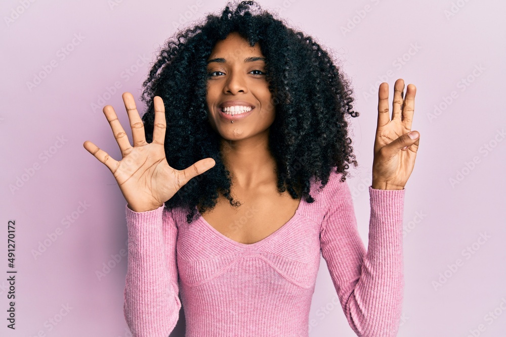 African american woman with afro hair wearing casual pink shirt showing and pointing up with fingers number eight while smiling confident and happy. African american woman with afro hair wearing casual pink shirt showing and pointing up with fingers number eight while smiling confident and happy.