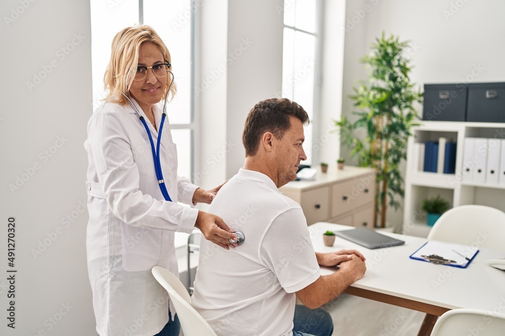 Fototapeta premium Middle age man and woman doctor and patient examining vision having medical consultation at clinic