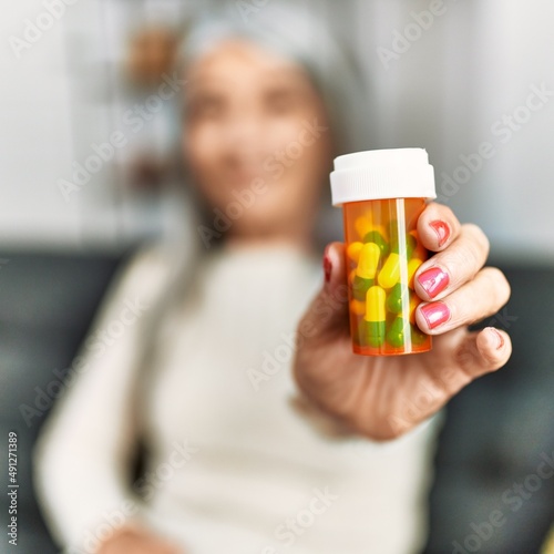 Middle age grey-haired woman smiling confident holding pills bottle at home