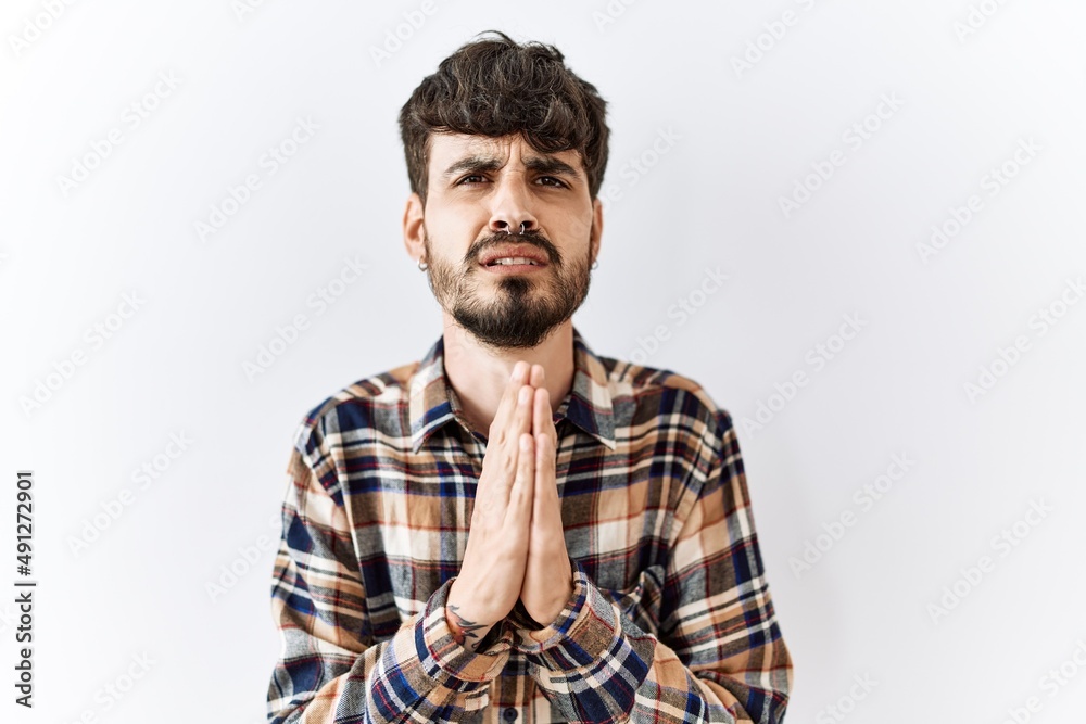 Obraz premium Hispanic man with beard standing over isolated background begging and praying with hands together with hope expression on face very emotional and worried. begging.