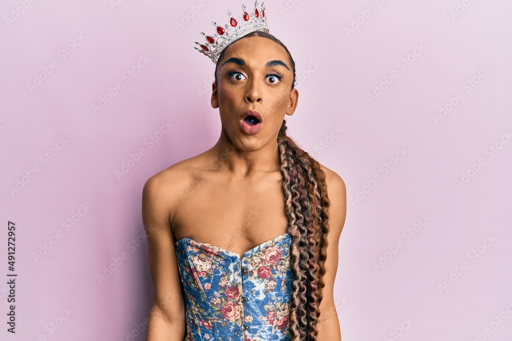 Hispanic man wearing make up and long hair wearing princess crown scared and amazed with open mouth for surprise, disbelief face Hispanic man wearing make up and long hair wearing princess crown scared and amazed with open mouth for surprise, disbelief face