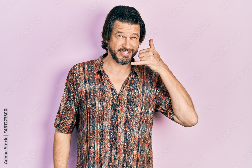 Middle age caucasian man wearing casual clothes smiling doing phone gesture with hand and fingers like talking on the telephone. communicating concepts. Middle age caucasian man wearing casual clothes smiling doing phone gesture with hand and fingers like talking on the telephone. communicating concepts.