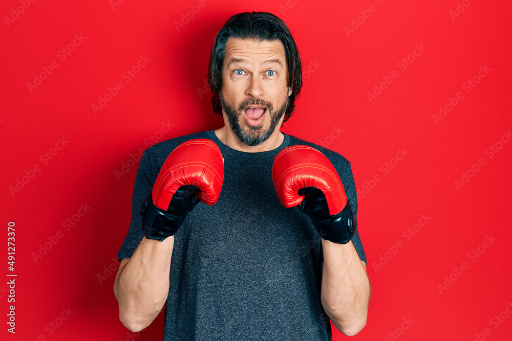 Middle age caucasian man using boxing gloves afraid and shocked with surprise and amazed expression, fear and excited face.