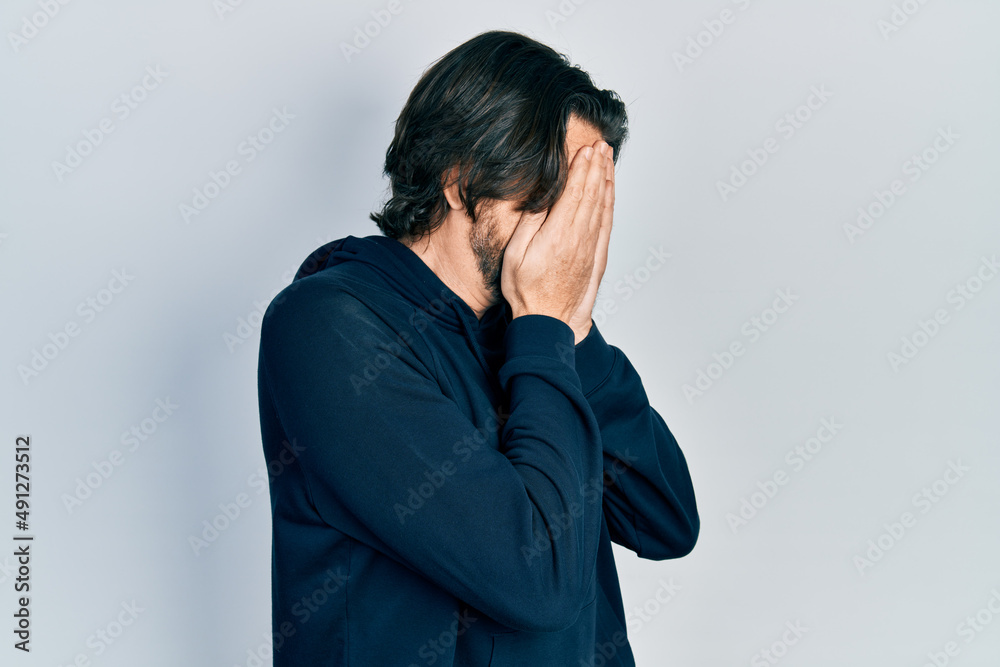 Middle age caucasian man wearing casual sweatshirt with sad expression covering face with hands while crying. depression concept. Middle age caucasian man wearing casual sweatshirt with sad expression covering face with hands while crying. depression concept.