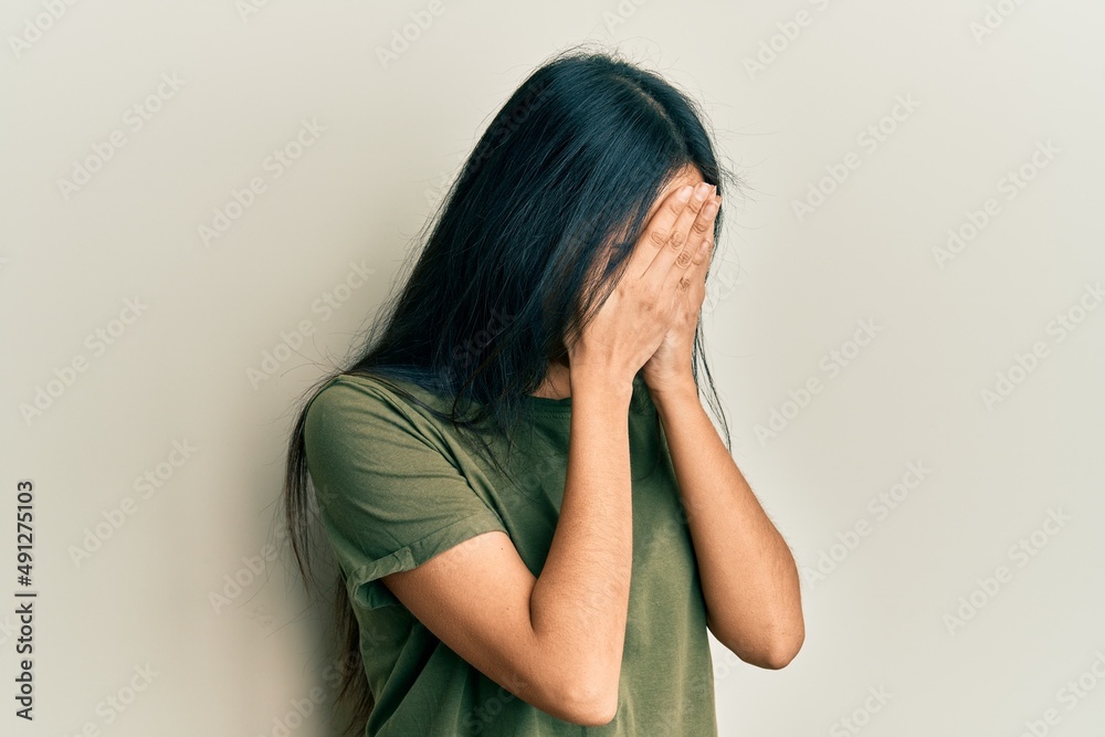 Young hispanic girl wearing casual t shirt with sad expression covering face with hands while crying. depression concept. Young hispanic girl wearing casual t shirt with sad expression covering face with hands while crying. depression concept.