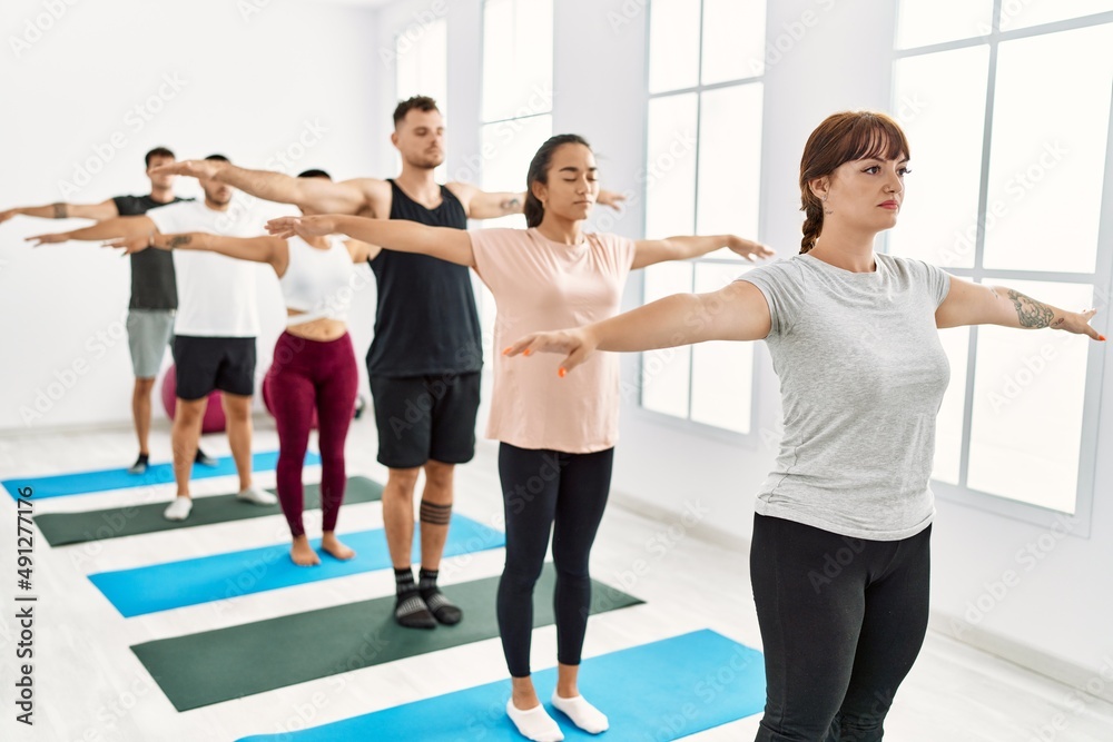 Naklejka premium Group of young hispanic people concentrate training yoga at sport center.