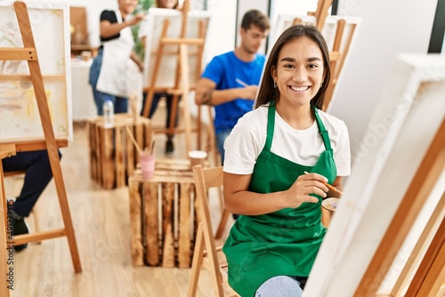 Young woman smiling happy drawing with group of people at art studio.