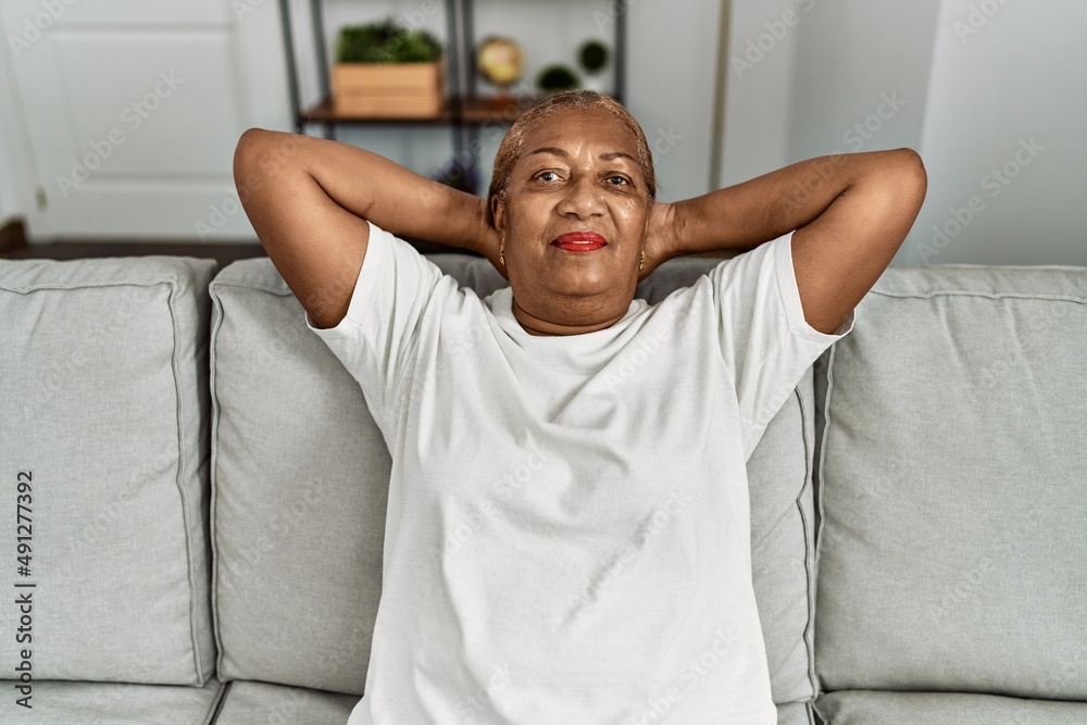 Senior african american woman relaxed with hands on head sitting on sofa at home Senior african american woman relaxed with hands on head sitting on sofa at home