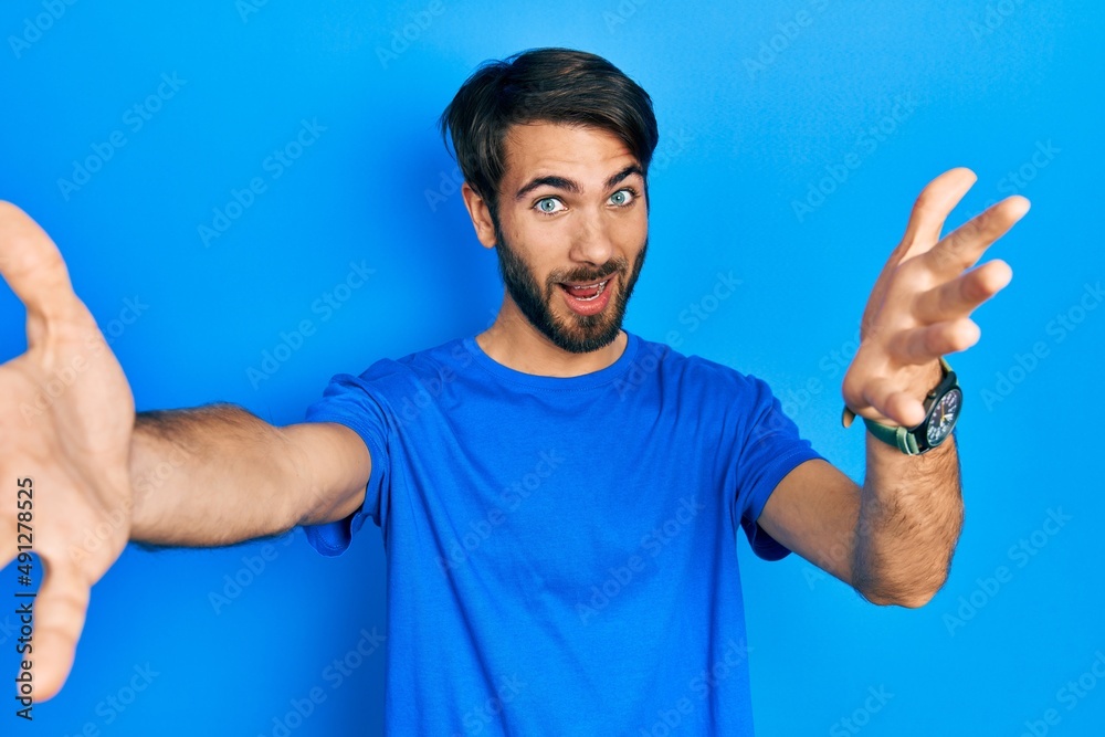 Young hispanic man wearing casual clothes looking at the camera smiling with open arms for hug. cheerful expression embracing happiness. Young hispanic man wearing casual clothes looking at the camera smiling with open arms for hug. cheerful expression embracing happiness.