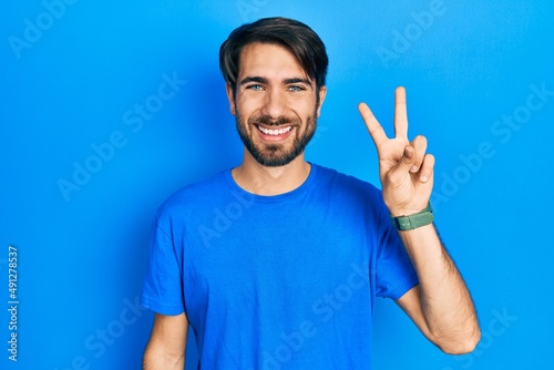 Young hispanic man wearing casual clothes showing and pointing up with fingers number two while smiling confident and happy.