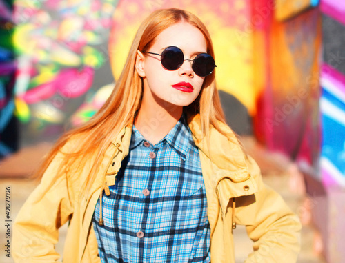 Fashion portrait of beautiful stylish blonde young woman on city street over colorful graffiti background © rohappy