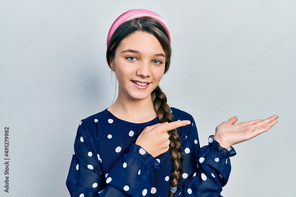 Young brunette girl wearing elegant look amazed and smiling to the camera while presenting with hand and pointing with finger. Young brunette girl wearing elegant look amazed and smiling to the camera while presenting with hand and pointing with finger.