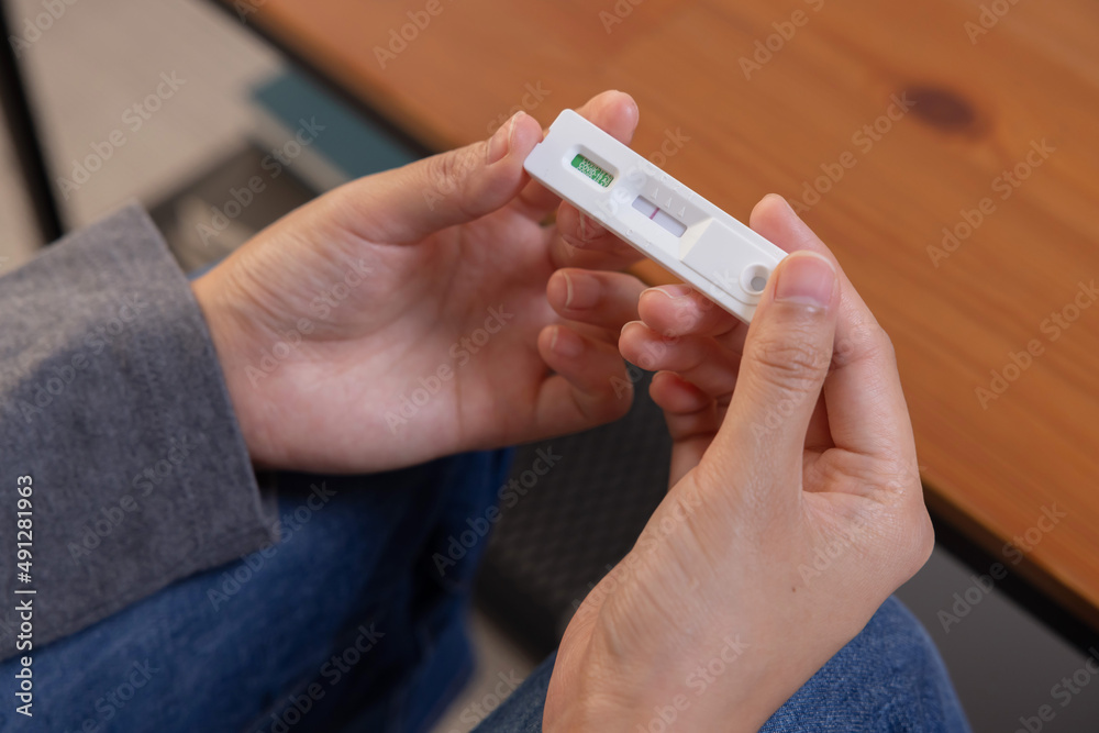 Woman Hand with ATK Antigen Test Kit Strip with Positive Result of Covid-19 Virus