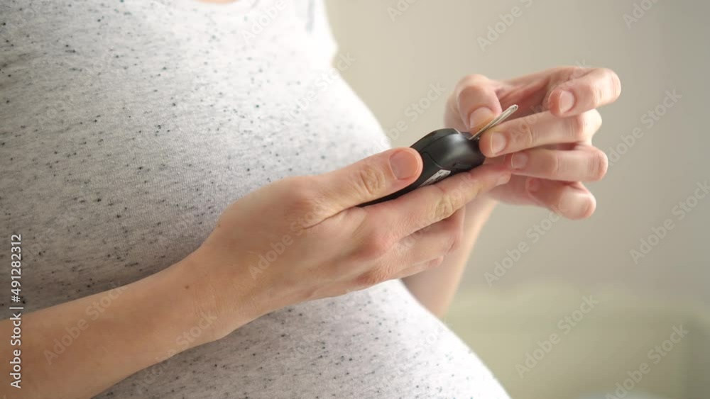 Pregnant woman holding glucose meter and checking sugar level. Concept of diabetes during pregnancy. Healthcare control. Diabetes checking blood sugar.