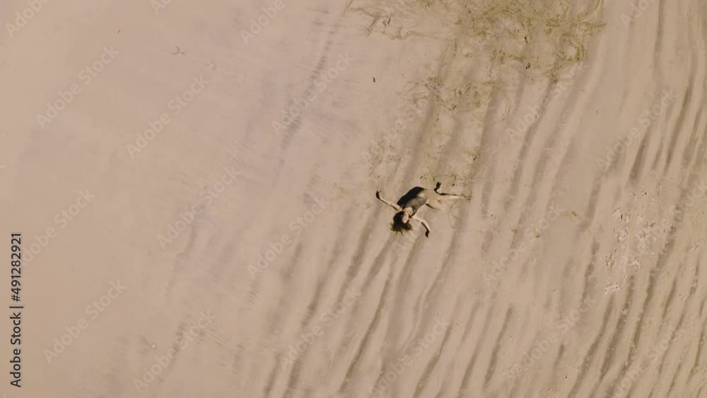 Somatic movement dance therapy on the beach, overhead aerial with woman practicing on the beach Somatic movement dance therapy on the beach, overhead aerial with woman practicing on the beach