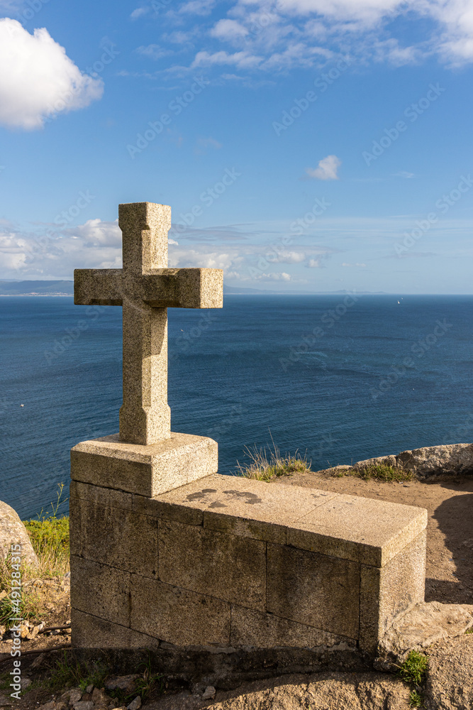 Stone cross at the end of the St. James way in Cape Finisterre, in Galicia, Spain. Religion and tourism concept.
