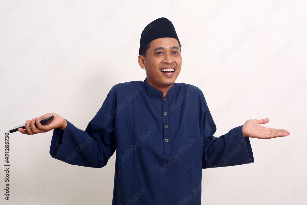 Happy asian man while standing and holding a phone cellular. Ramadan concept Happy asian man while standing and holding a phone cellular. Ramadan concept