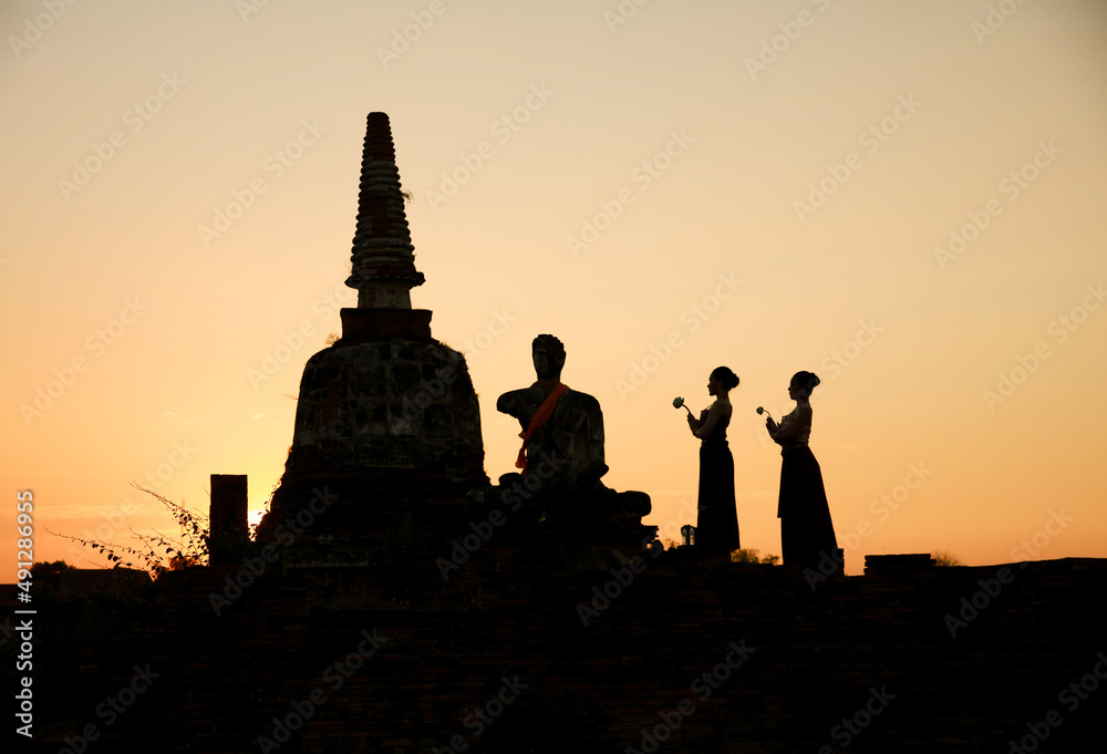 Silhouette Two sister hold lotus flower respect ancient buddha status at front Pagoda , Thailand Culture at Historical Park, Ayutthaya, 