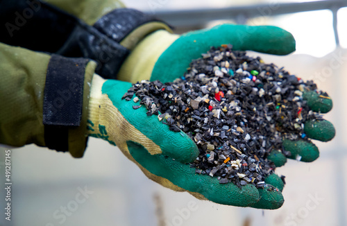 Close up of granulated plastic waste on a recycling plant for plastics. Plastic recycling factoring. Shreddered plastic granules. Hands with granulated plastic. Recycling plant.