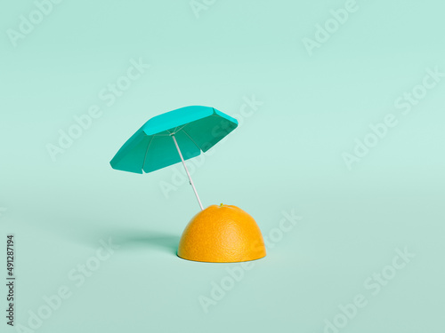 half orange with an umbrella stuck in it