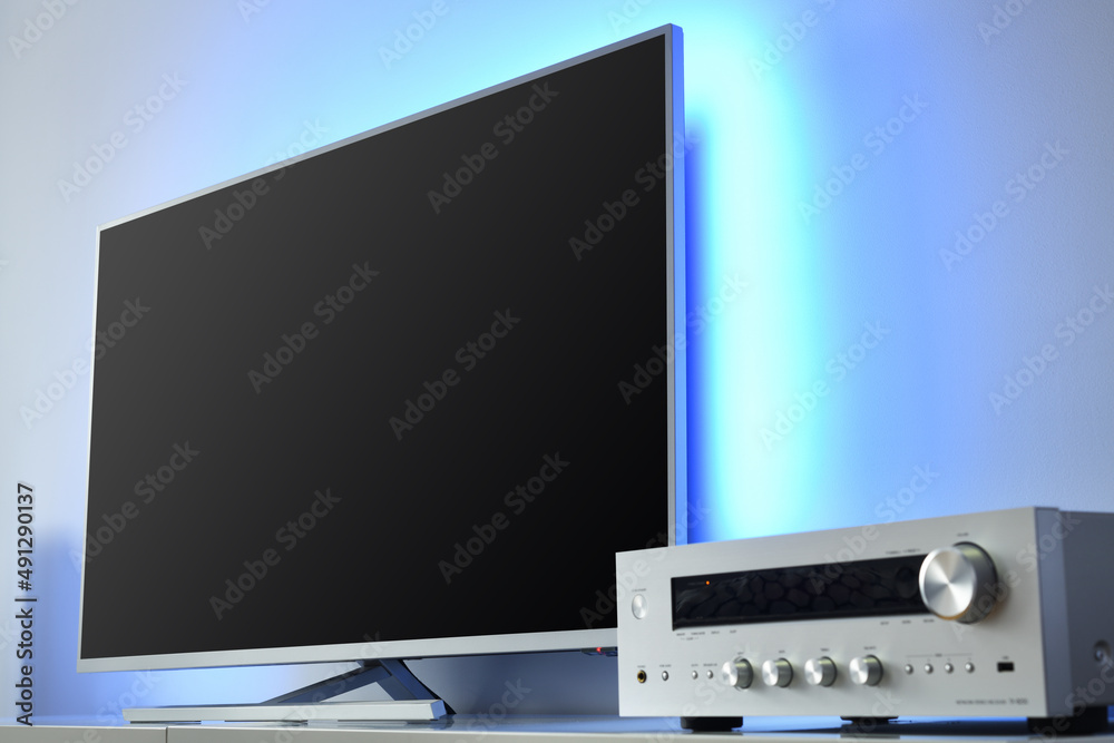 Large LED TV with backlight and audio receiver in a modern apartment. 