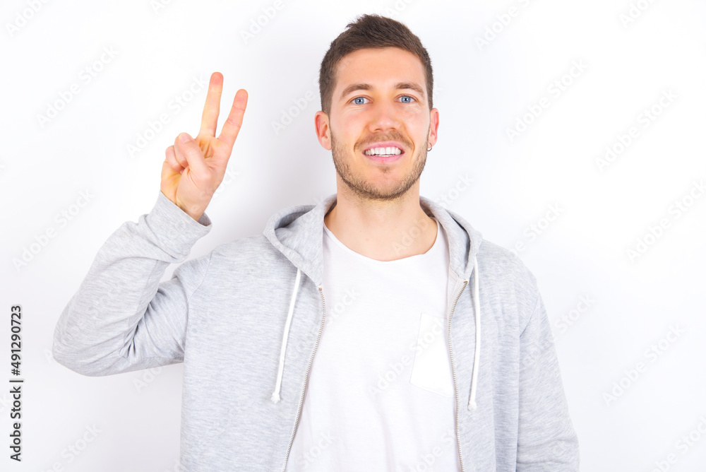 young caucasian man wearing casual clothes over white background showing and pointing up with fingers number two while smiling confident and happy. young caucasian man wearing casual clothes over white background showing and pointing up with fingers number two while smiling confident and happy.