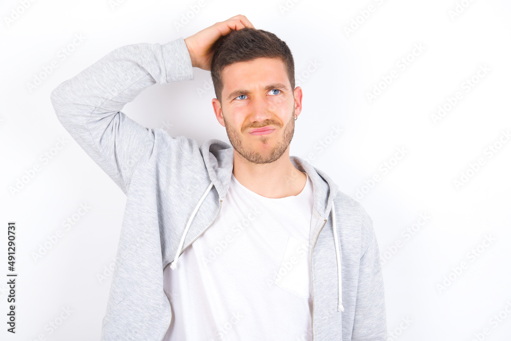 young caucasian man wearing casual clothes over white background saying: Oops, what did I do? Holding hand on head with frightened and regret expression. young caucasian man wearing casual clothes over white background saying: Oops, what did I do? Holding hand on head with frightened and regret expression.