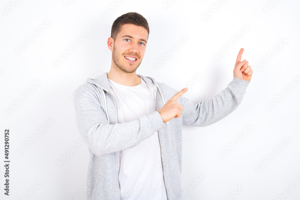 young caucasian man wearing casual clothes over white background with positive expression, indicates with fore finger at blank copy space for your promotional text or advertisement. young caucasian man wearing casual clothes over white background with positive expression, indicates with fore finger at blank copy space for your promotional text or advertisement.