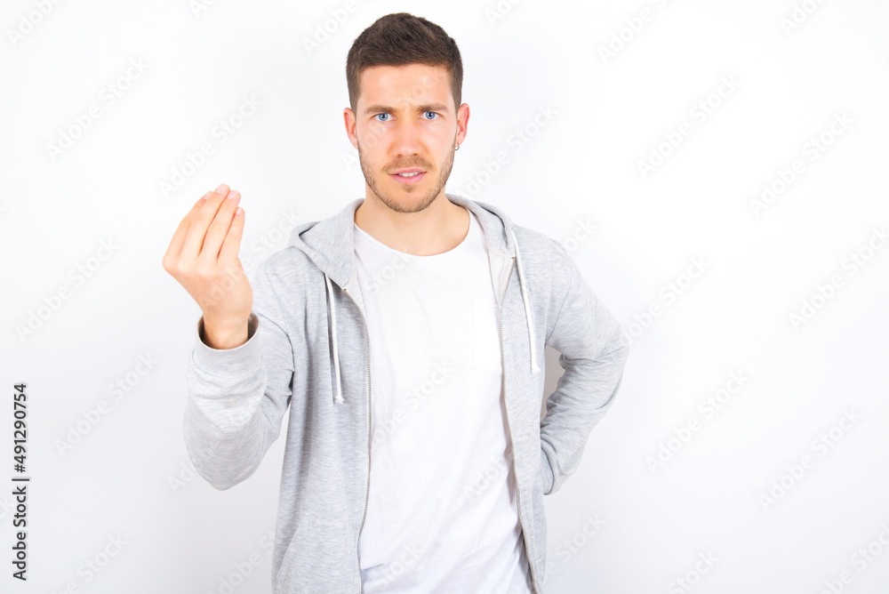 What the hell are you talking about. Shot of frustrated young caucasian man wearing casual clothes over white background gesturing with raised hand doing Italian gesture, frowning, being displeased What the hell are you talking about. Shot of frustrated young caucasian man wearing casual clothes over white background gesturing with raised hand doing Italian gesture, frowning, being displeased